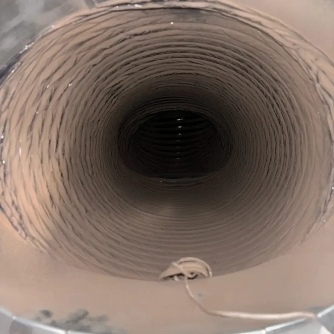 Inside a duct run showing dust coating the wall before cleaning