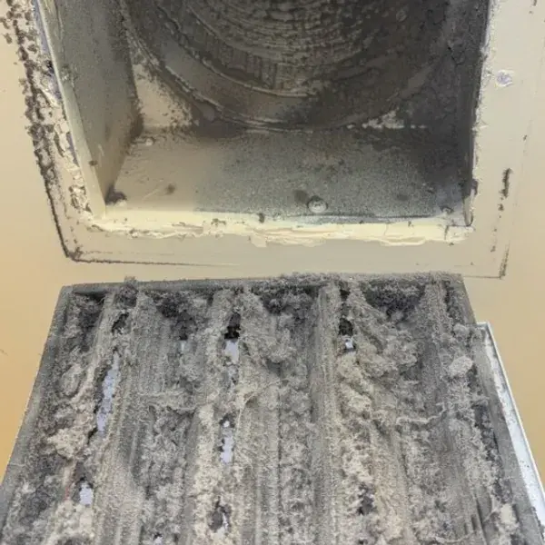 Return vent opening with the grille removed, both packed with dust and debris before cleaning