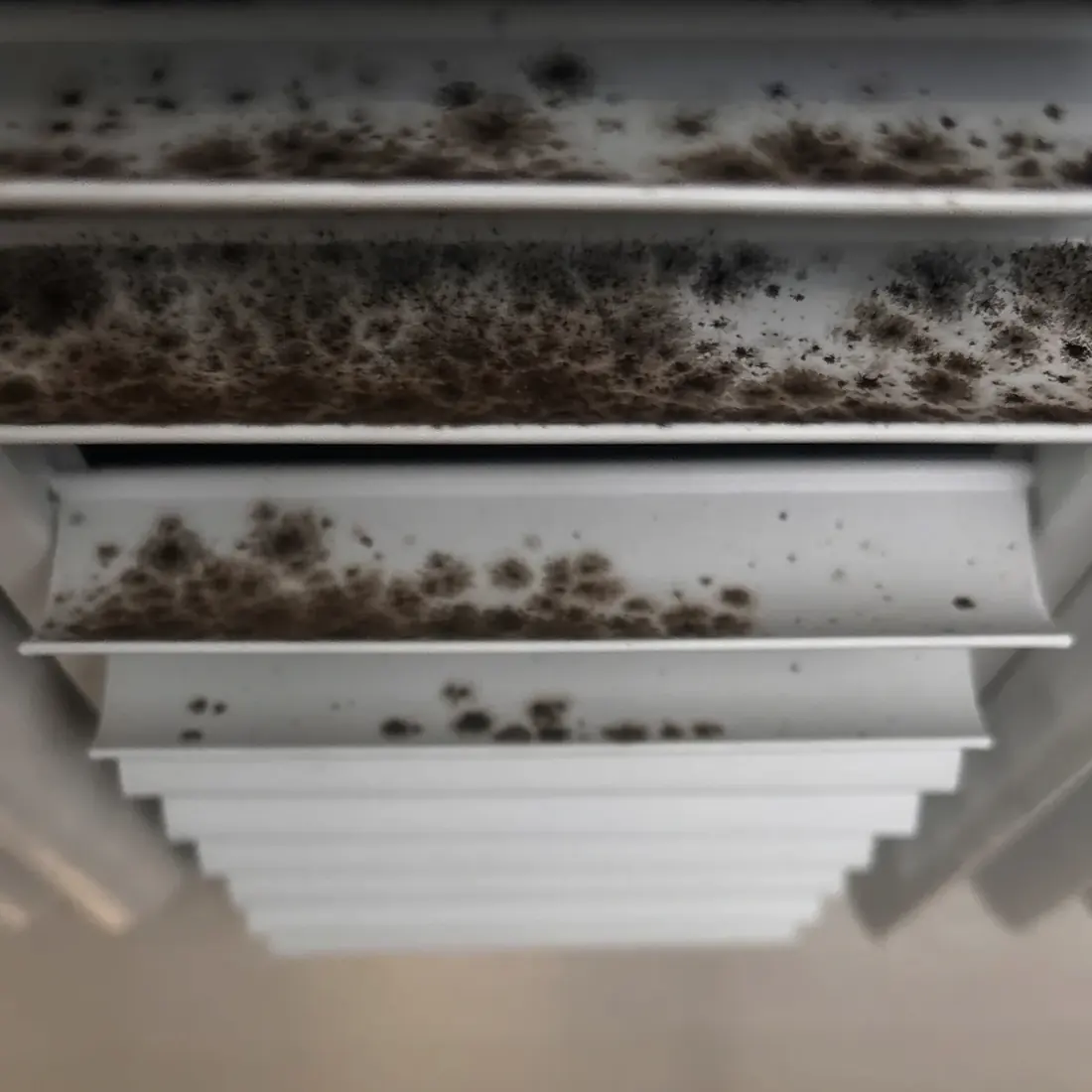 Supply register with heavy dust and debris built up across the vanes before cleaning