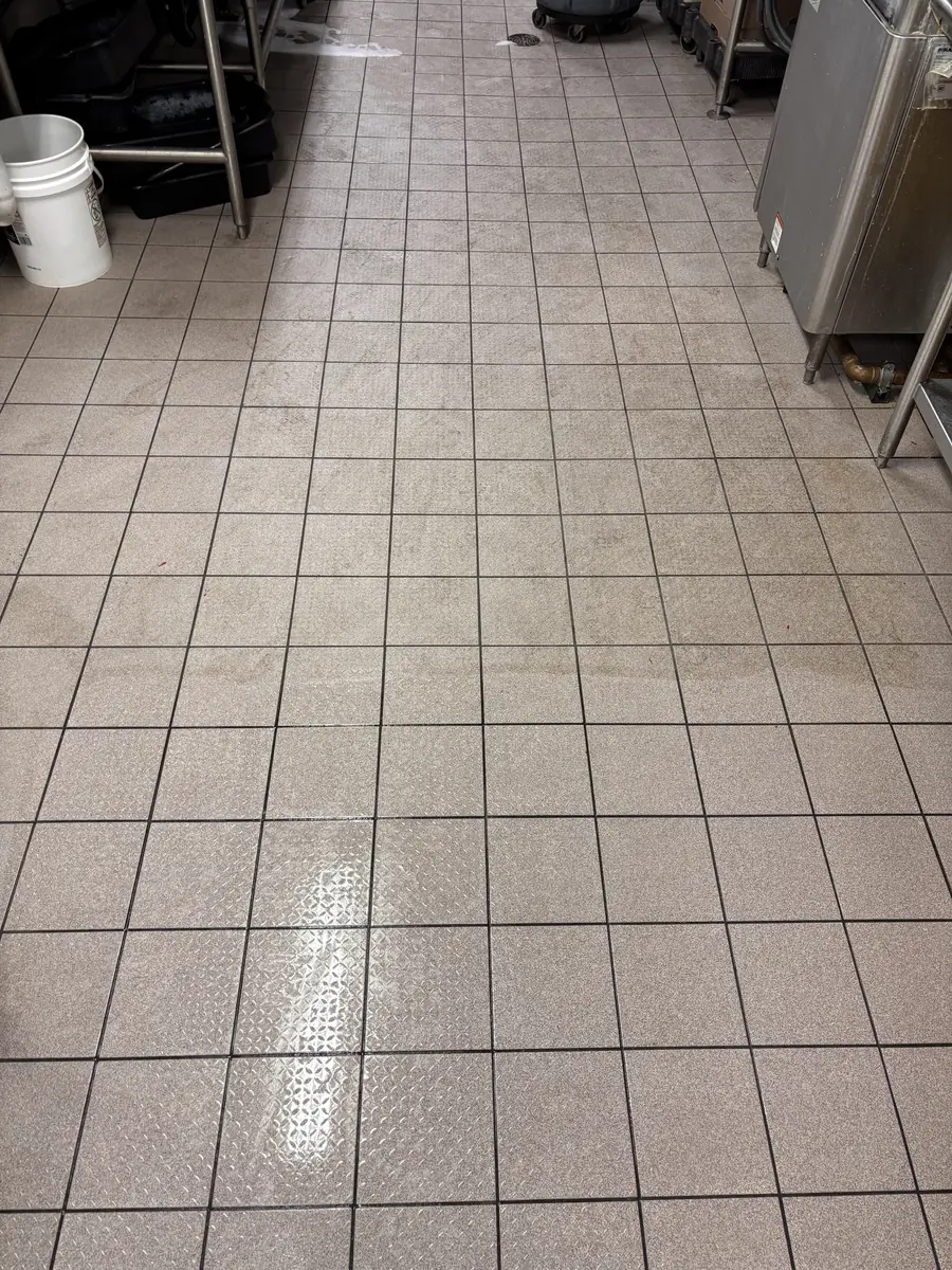 Commercial kitchen tile mid-clean, the clean line against the soiled side