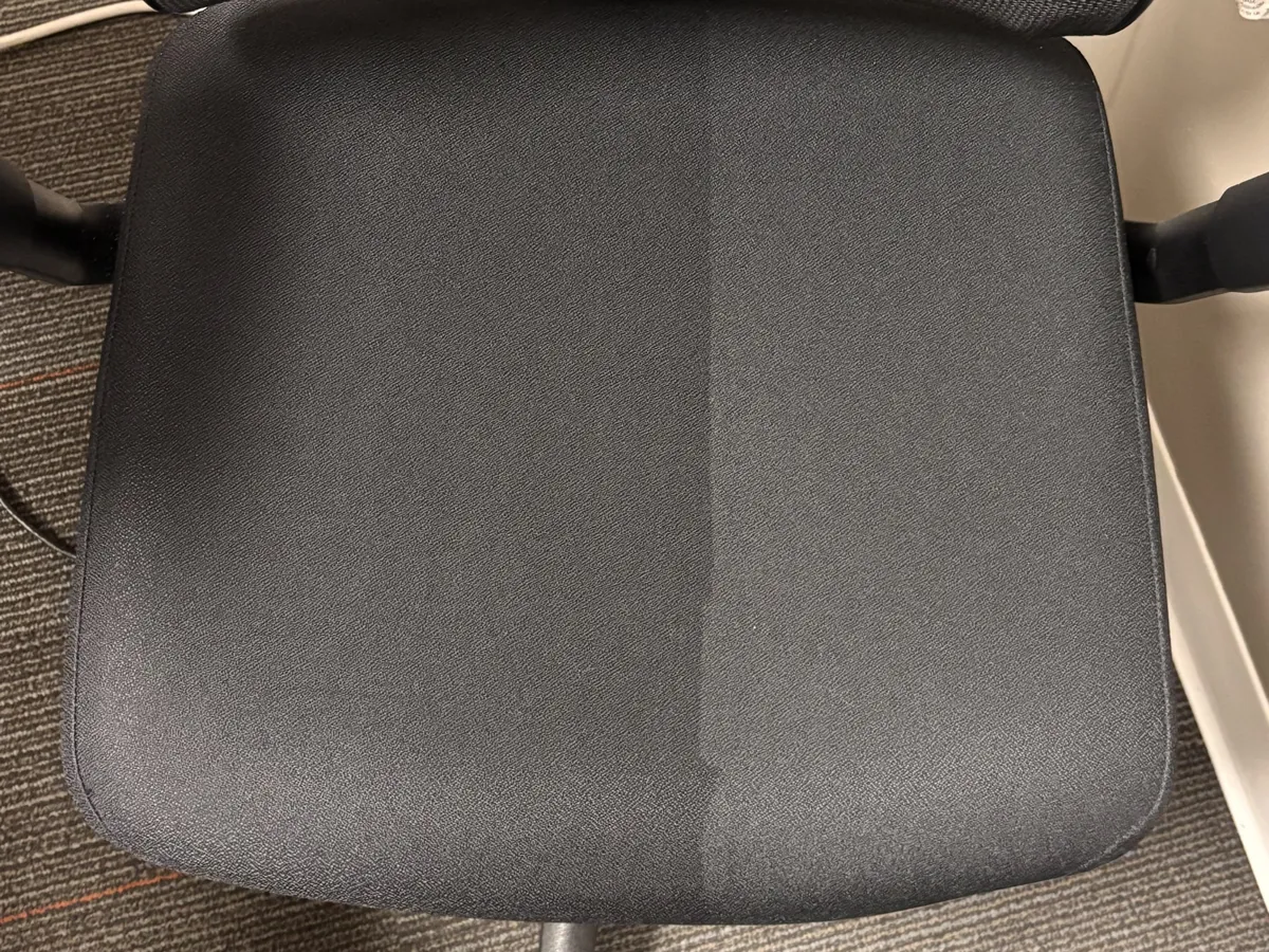 Office chair seat mid-clean, the cleaned half against the soiled half