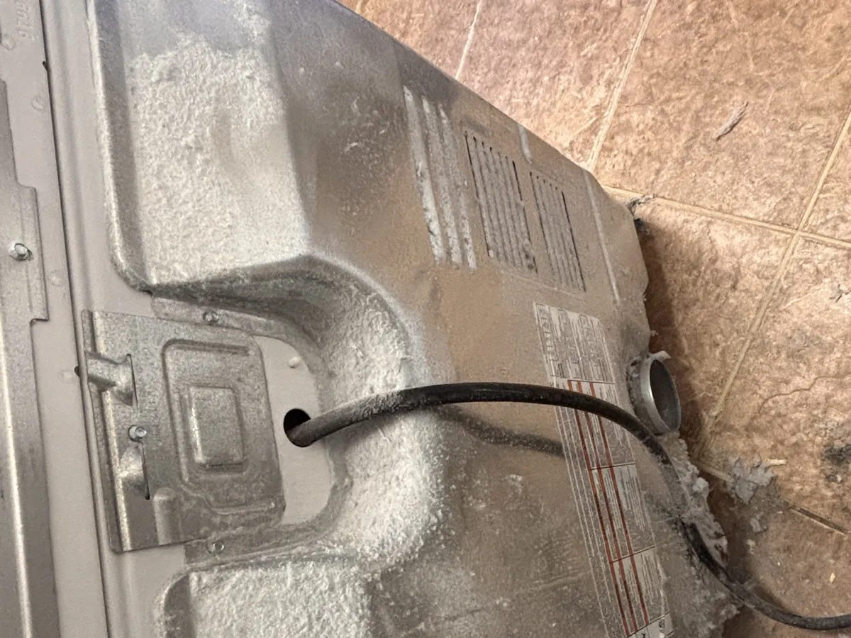 Lint caked behind a dryer back panel