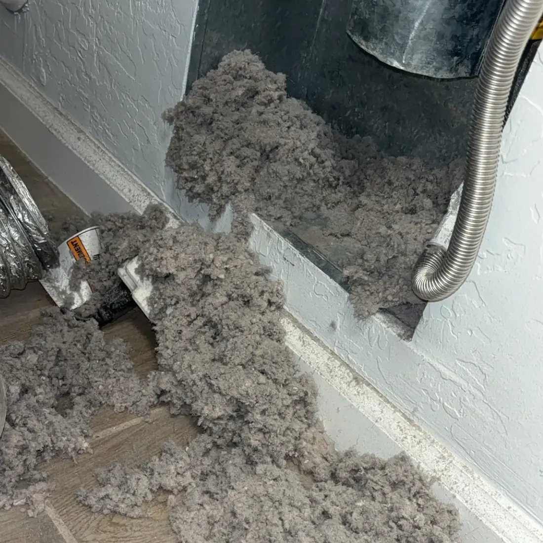 Lint spilling out of a wall vent opening