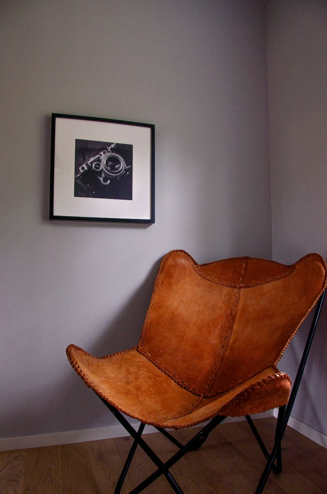 Tan leather butterfly chair with hand-stitched seams on a black metal frame, leather furniture cleaning in Apache Junction AZ