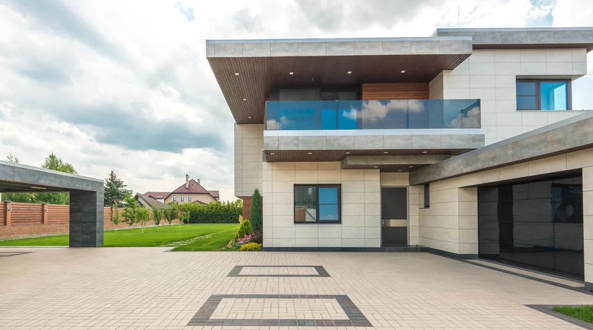 Light paver driveway with a darker border pattern in front of a modern home