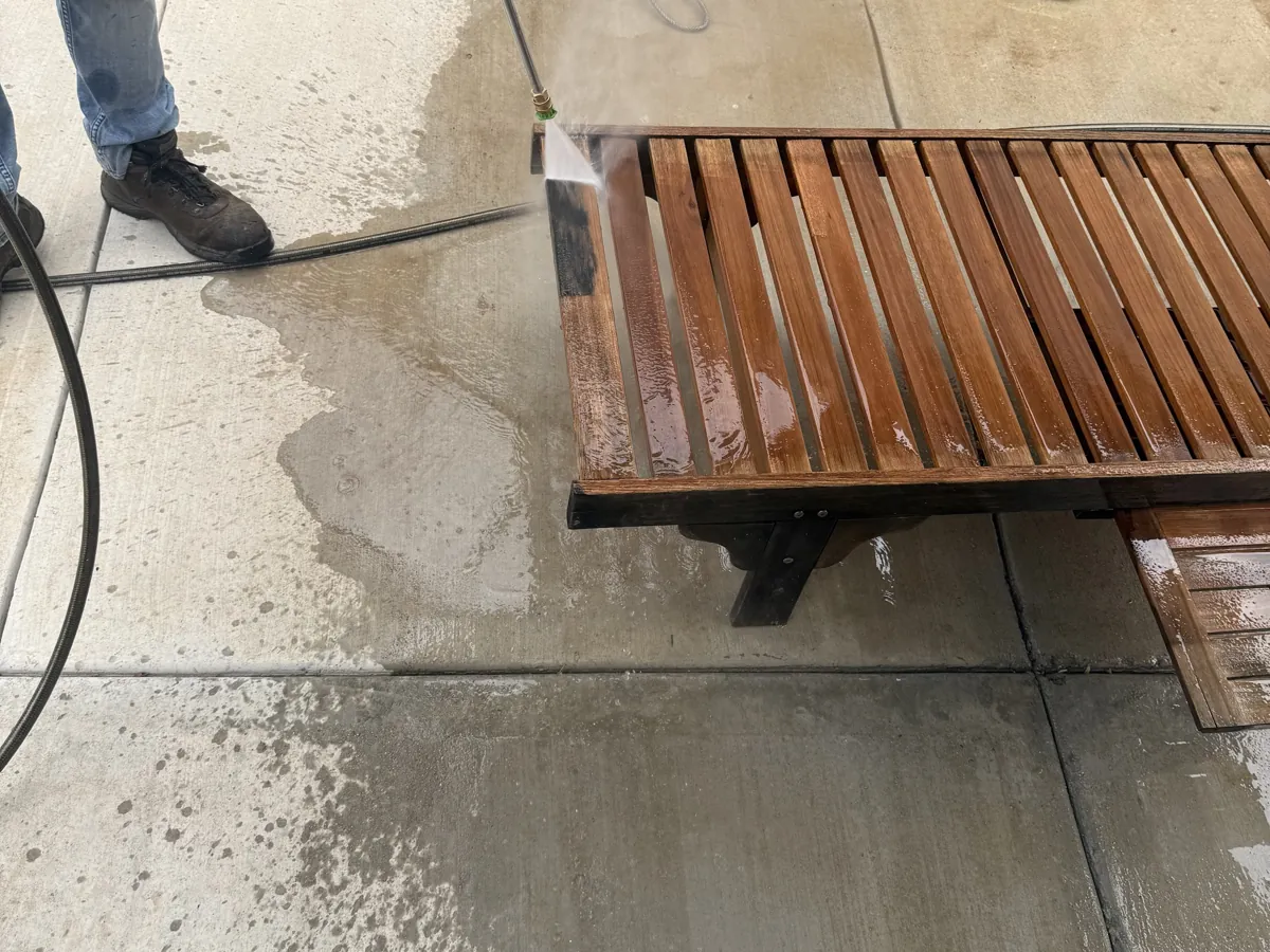 Teak bench mid-wash, the clean line against the weathered side