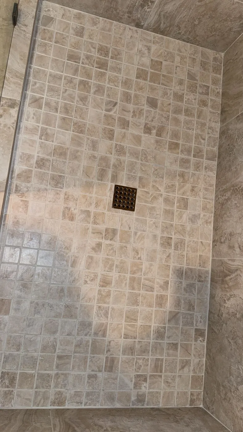 Square travertine mosaic shower pan after grout color sealing