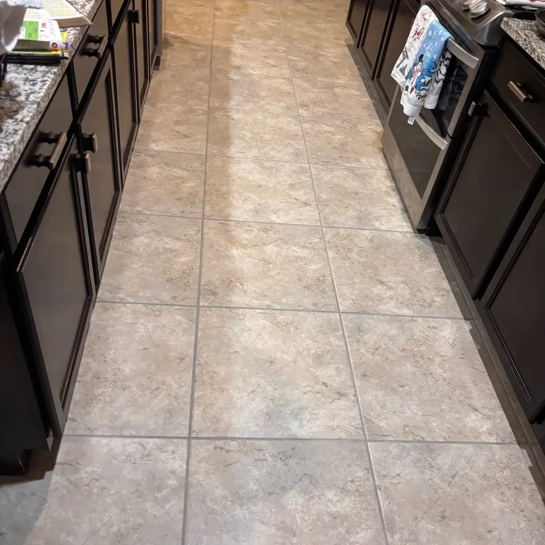 Cleaned kitchen tile floor with uniform grout lines between dark cabinets