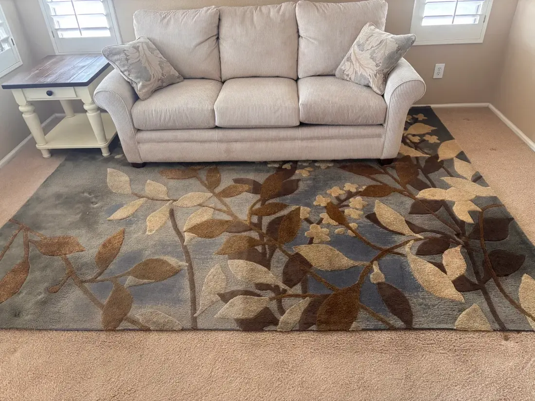 Tufted wool rug with a leaf pattern cleaned in place over carpet